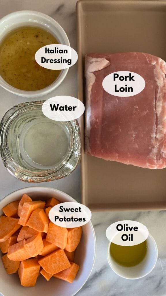 Ingredients for cooking laid out on a countertop: italian dressing, pork loin, sweet potatoes, olive oil, and a jar of water.
