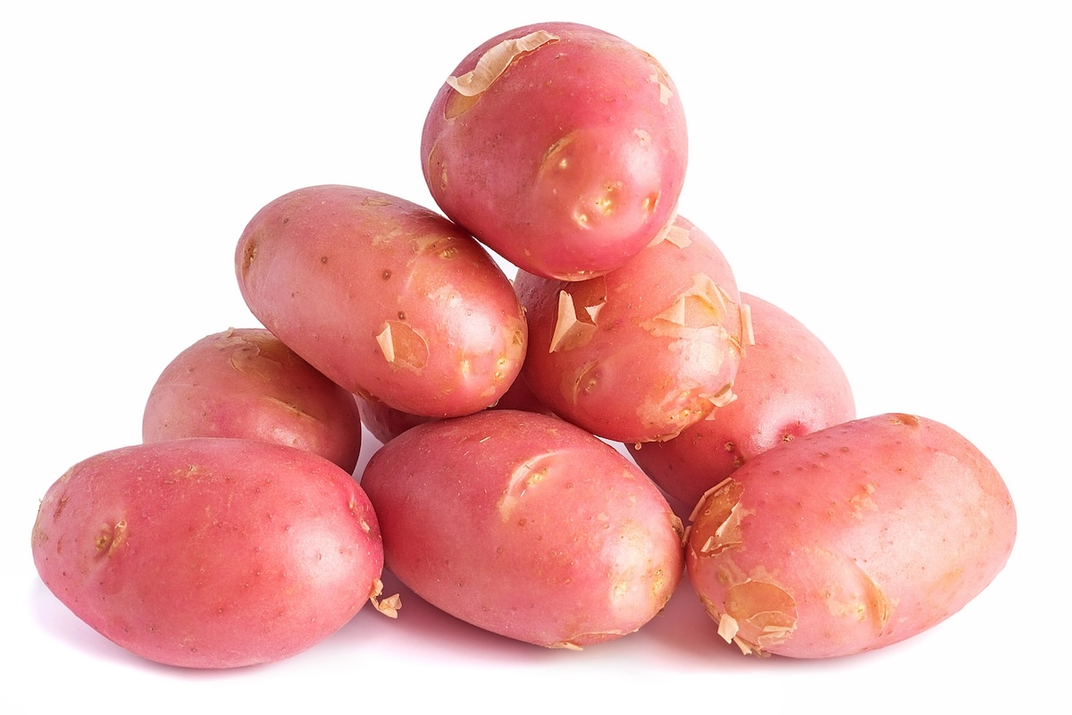 A pile of red potatoes with patchy skin, some peeling off, stacked against a white background.