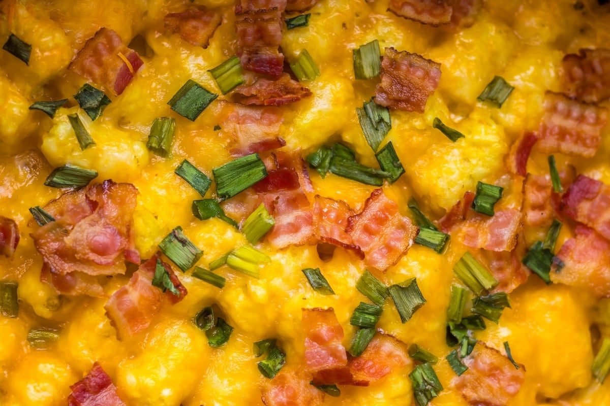 Close-up of scrambled eggs topped with chopped bacon and green onions.