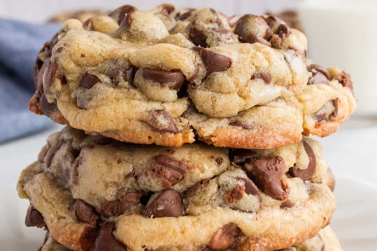 Stack of three chocolate chip cookies on a white surface.
