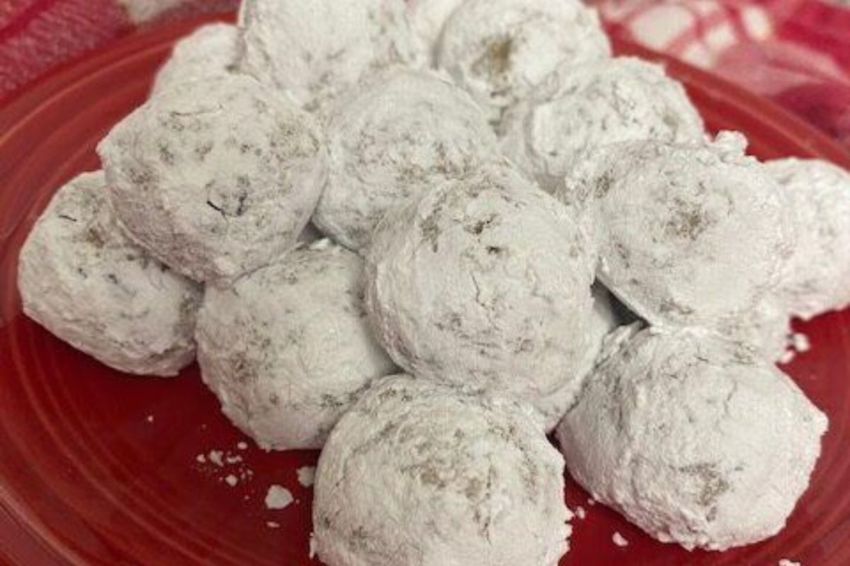 A stack of round cookies covered in powdered sugar on a red plate.