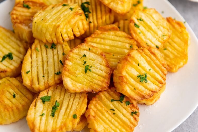 Crispy crinkle-cut potatoes garnished with parsley on a white plate.