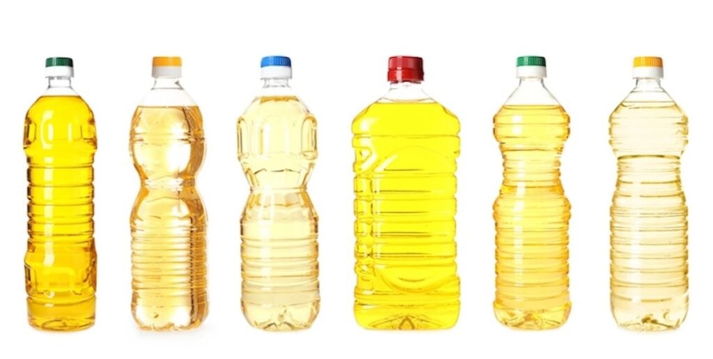 Six plastic bottles filled with various shades of yellow liquid, likely cooking oil, against a white background.