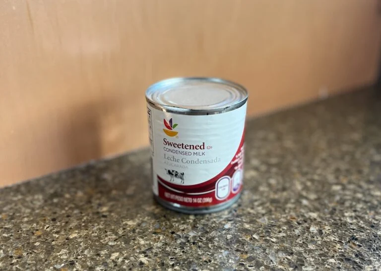 A can of sweetened condensed milk with a red and white label rests on a speckled countertop, tempting you to explore condensed milk substitutes for your next culinary creation.