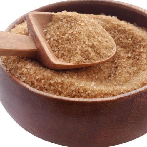 A wooden bowl filled with brown sugar and a wooden scoop.