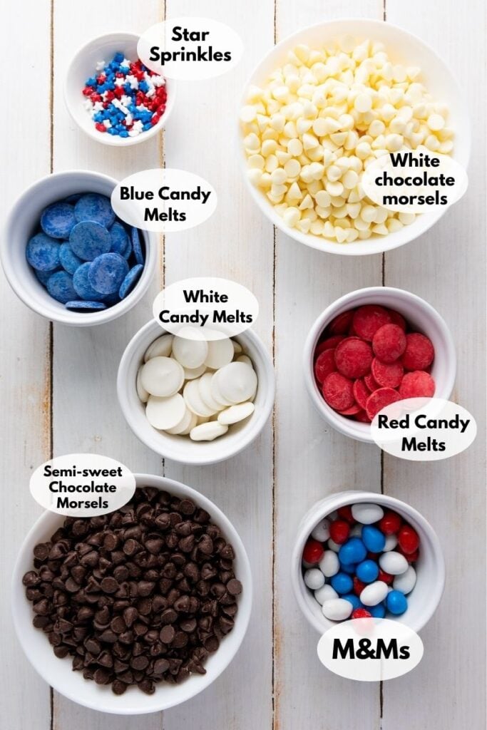 Assorted candy and chocolate in bowls including star sprinkles, white chocolate morsels, blue and red candy melts, white candy melts, semi-sweet chocolate morsels, and red, white, and blue M&M's.