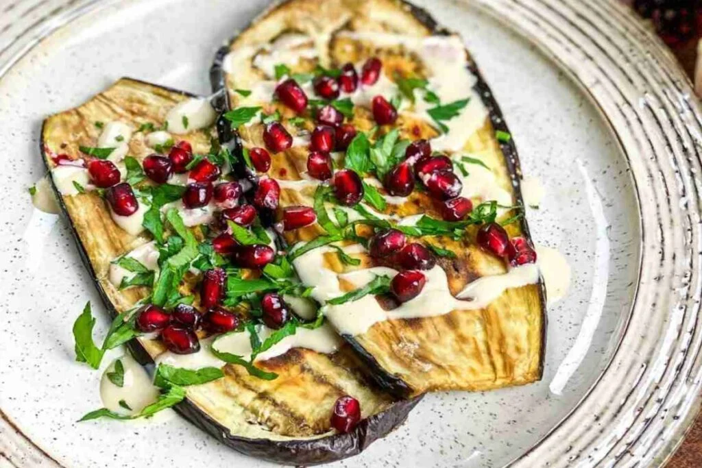 Tahini drizzled over roasted eggplant and topped with pomagranate seeds.