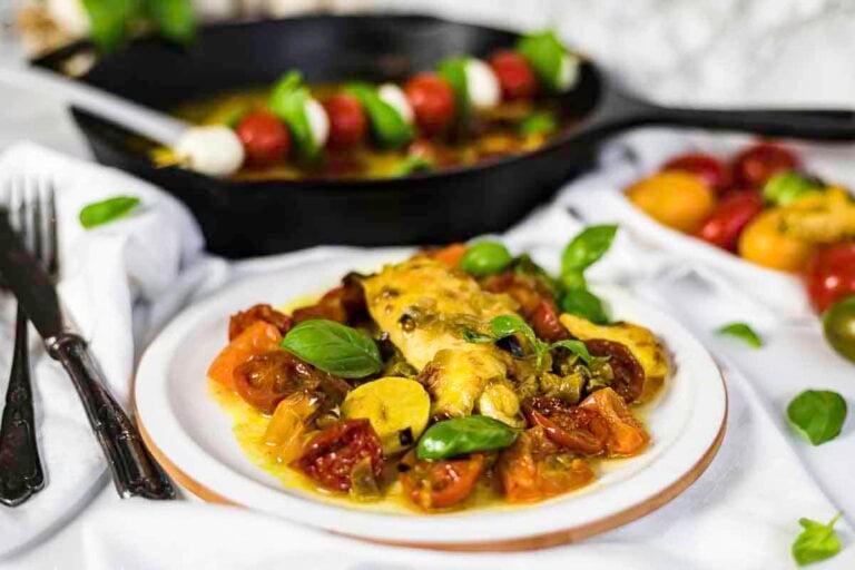 A plate of baked chicken breast with tomatoes, basil, and mozzarella.