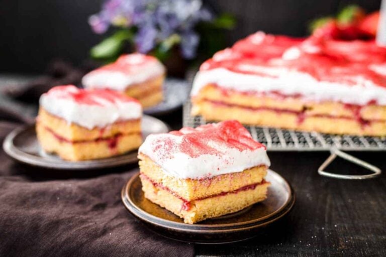 A slice of strawberry sheet cake with white frosting.