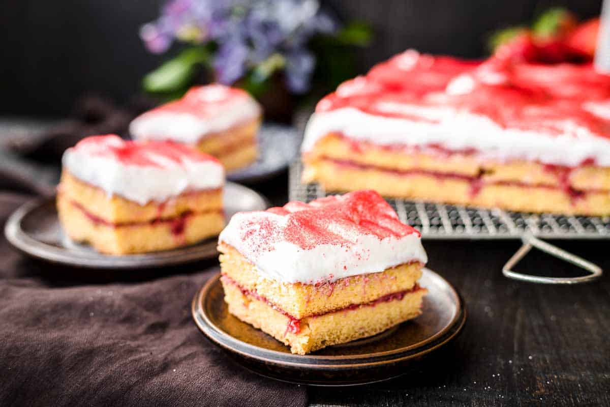 A slice of strawberry sheet cake with white frosting.