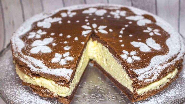 A chocolate sponge cake with a creamy filling, decorated with powdered sugar patterns, and one slice removed to show the inside.
