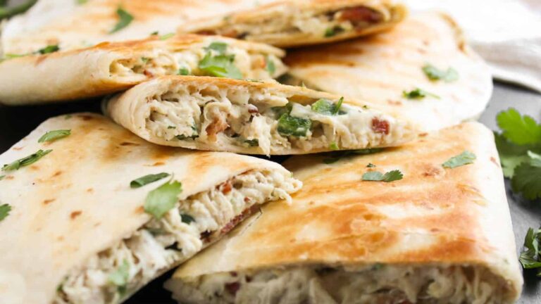 Several folded quesadillas filled with shredded chicken, herbs, and melted cheese, garnished with fresh cilantro.