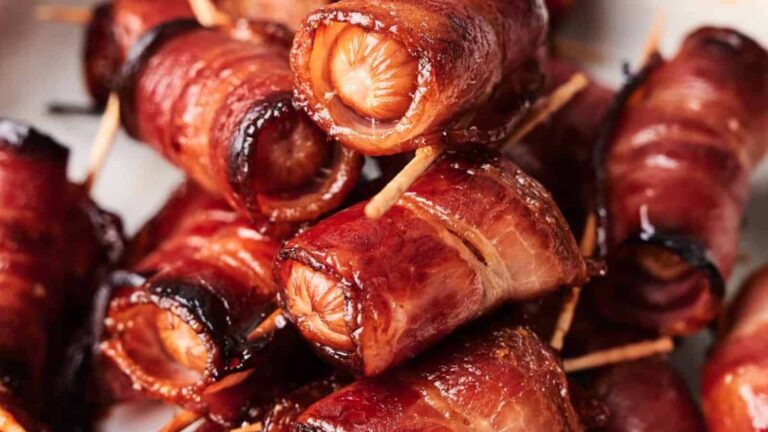 A close-up of Bacon Wrapped Sugar Smokies, held together with toothpicks and cooked to a crispy finish.