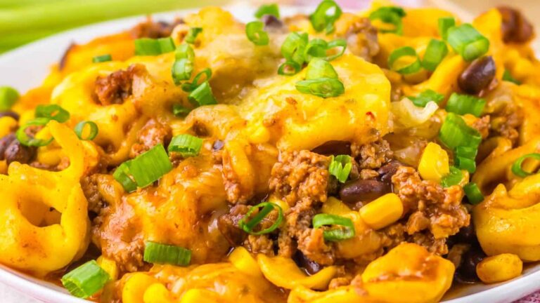 Close-up of a Beef Enchilada Tortellini dish topped with ground meat, corn, black beans, and chopped green onions.