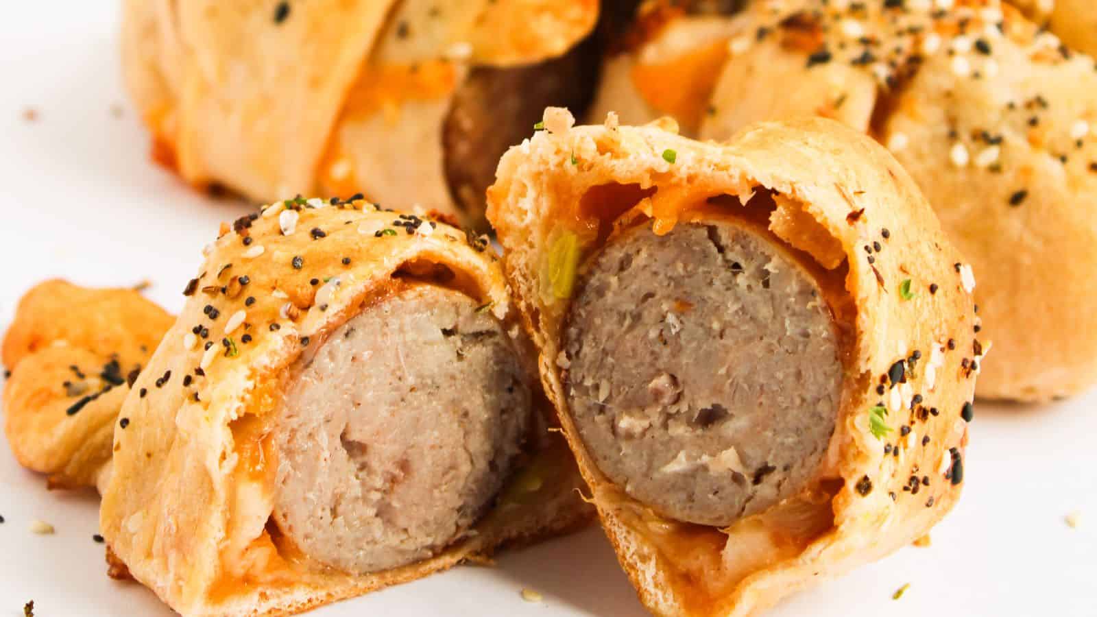 Sliced sausage wrapped in golden-brown pastry, sprinkled with sesame and poppy seeds.