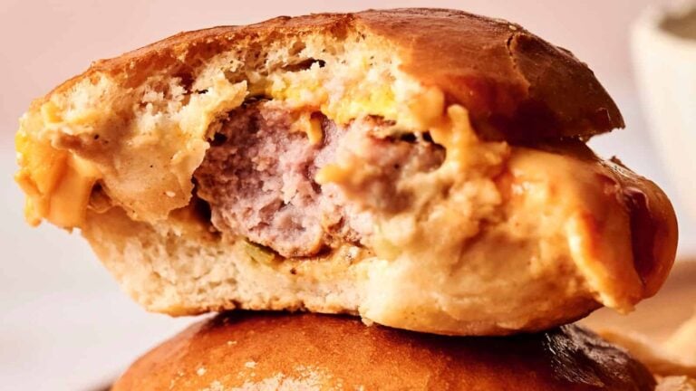 A close-up of a cheeseburger with a bite taken out, showing the beef patty, melted cheese, and bun.