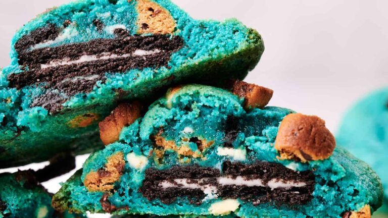 A close-up of blue cookies filled with chocolate sandwich cookies and chocolate chips, broken in half to show the inside.