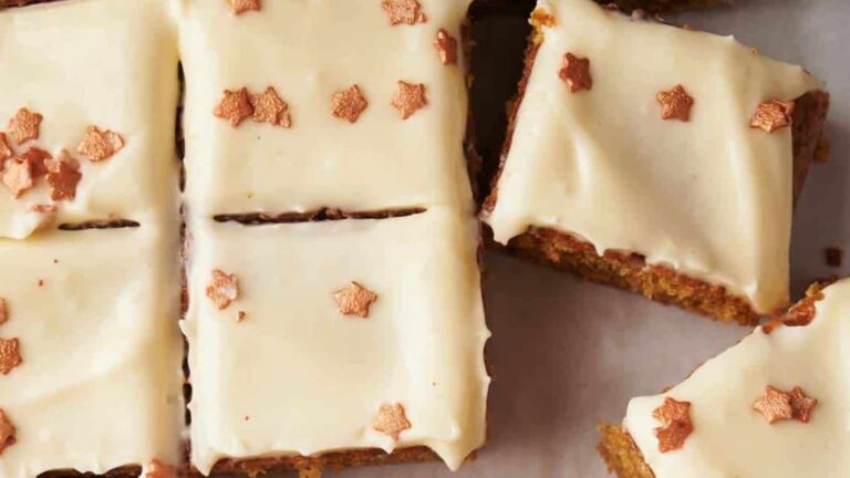 Rectangular slices of cake with white icing, topped with small, star-shaped decorations on a white surface.