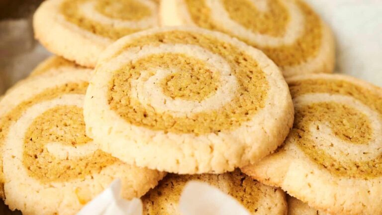 A close-up view of several golden-brown pinwheel cookies with visible spiral patterns stacked together.