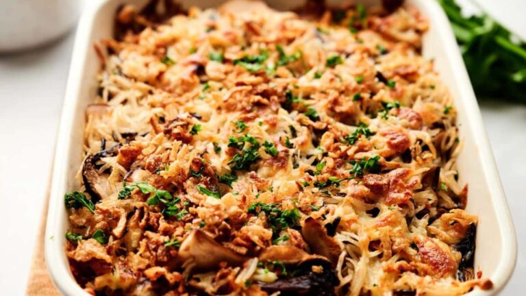 A baked casserole topped with crispy fried onions and chopped parsley is shown in a rectangular dish.