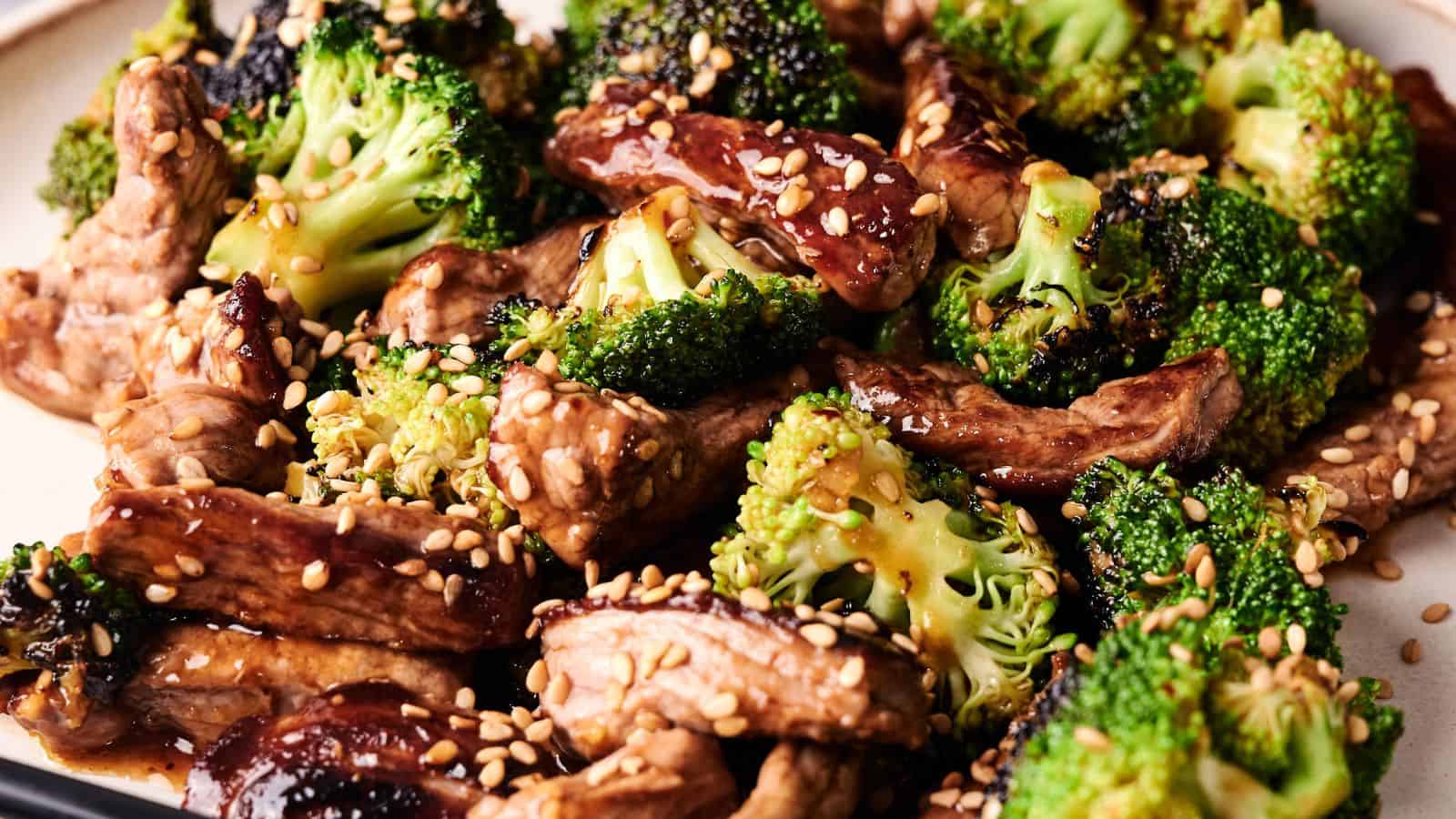 A plate of beef and broccoli stir-fry garnished with sesame seeds, featuring glazed beef strips and broccoli florets.