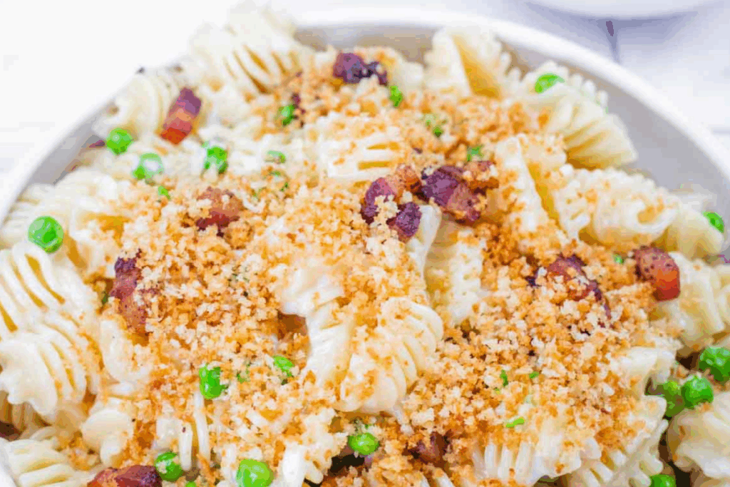 Lemon Pasta with Peas & Pancetta, topped with golden toasted breadcrumbs and served in a white bowl.