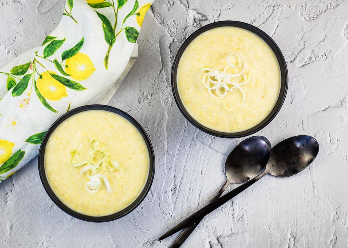 Two bowls of cream of leek & green garlic soup with spoons.