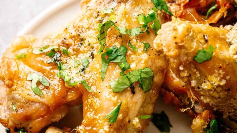 Close-up of crispy baked chicken wings garnished with chopped fresh parsley on a white plate.