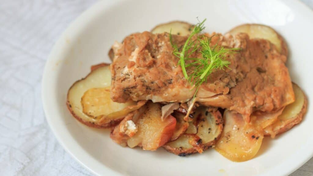 A plate featuring a serving of potatoes alongside cooked salmon, arranged appetizingly.