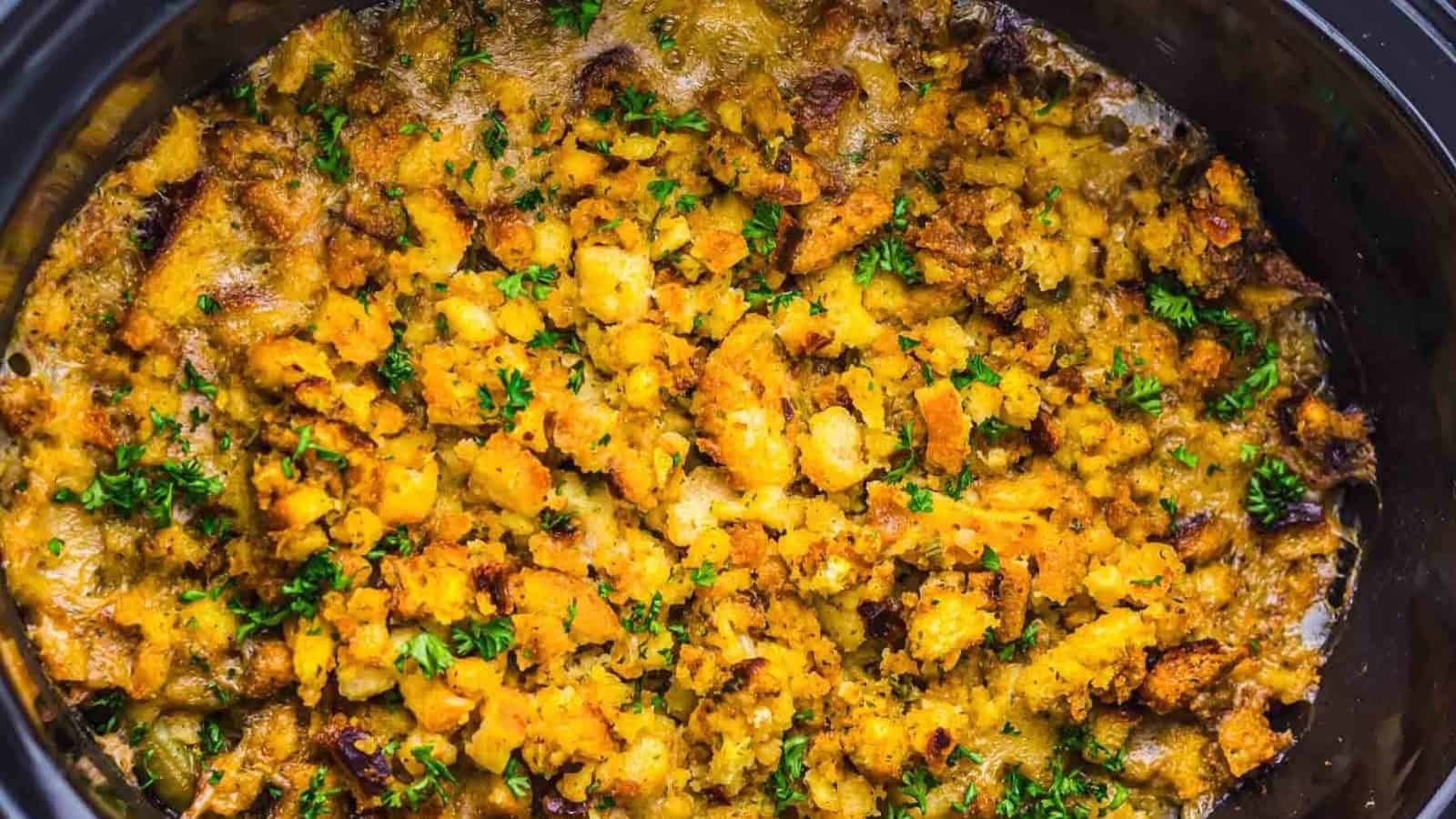 Golden-brown stuffing topped with chopped herbs, baked until crispy in a black dish.