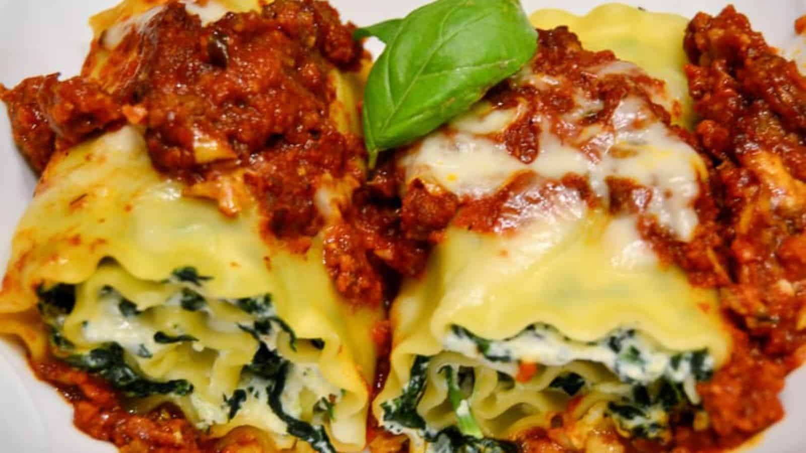 Two lasagna roll-ups filled with spinach and ricotta cheese, topped with tomato sauce and melted cheese.