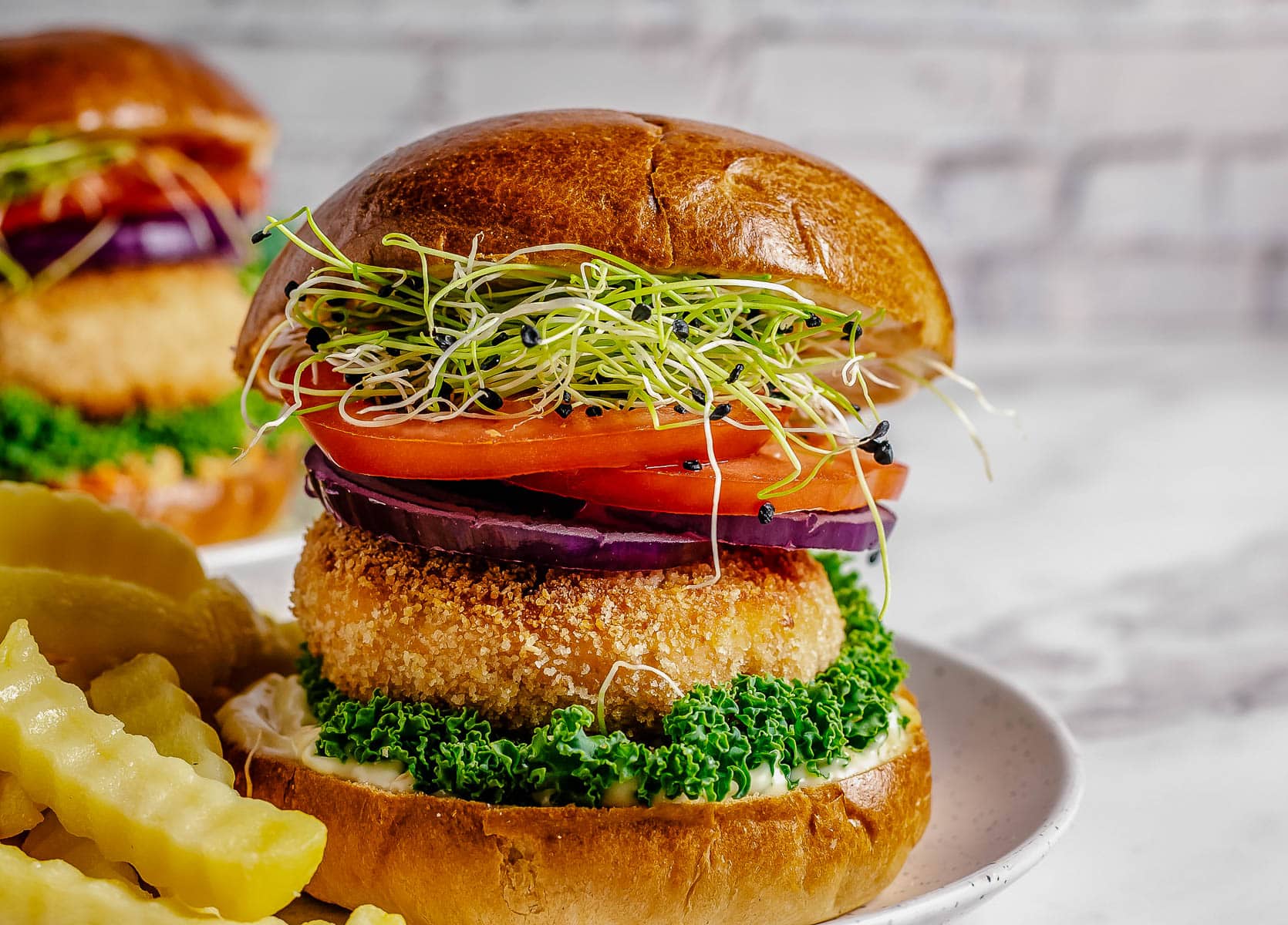 Air fryer salmon patties on a bun with tomatoes, sprouts and lettuce.
