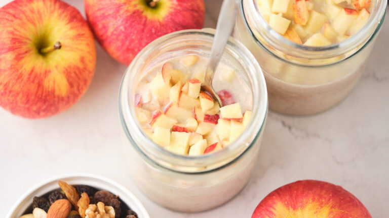 Two glass jars of overnight oats topped with chopped apples.