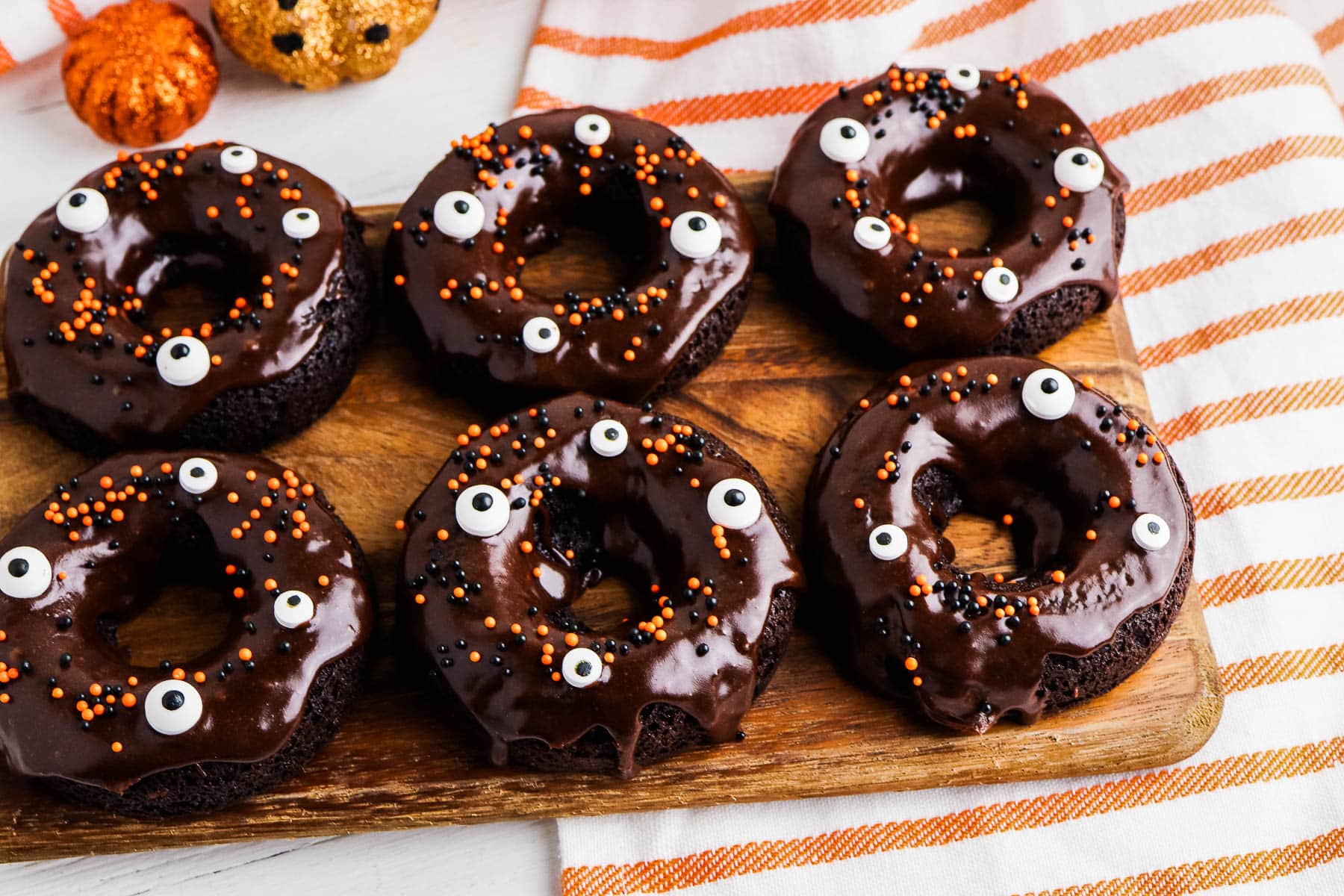 Chocolate cake mix donuts with colorful sprinkles on a baking rack.