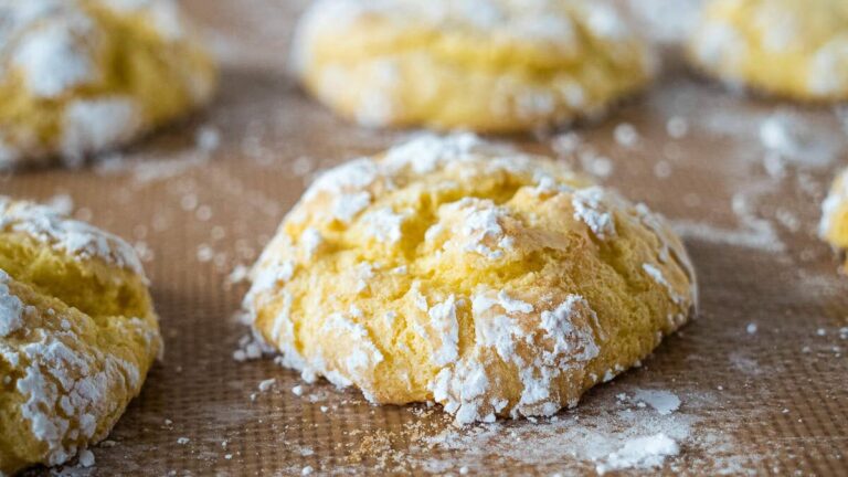 Cool whip cookies on parchment with powdered sugar.