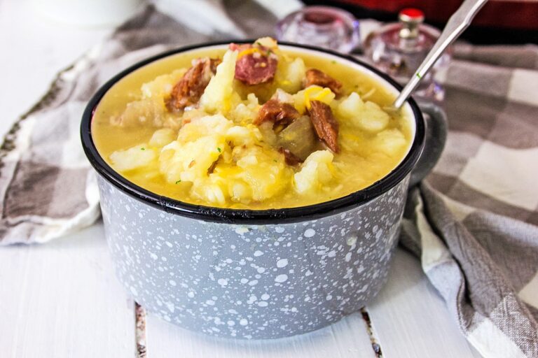 Ham and Potato soup in a gray and white bowl with a spoon.
