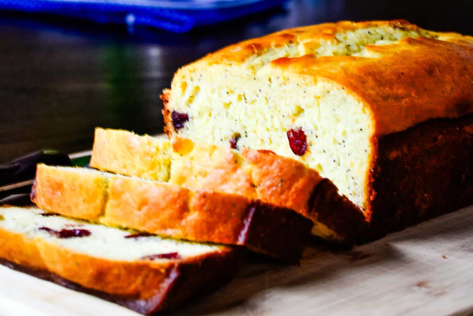 A loaf of cranberry orange poppy seed bread on a cutting board.