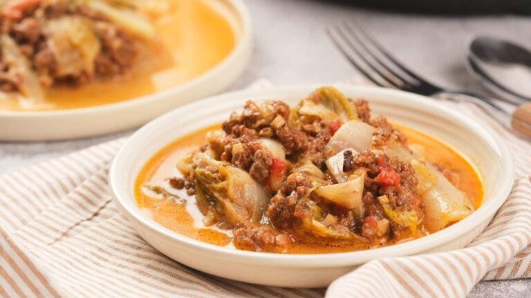 A plate of cabbage roll casserole with ground meat, onions, and tomatoes.