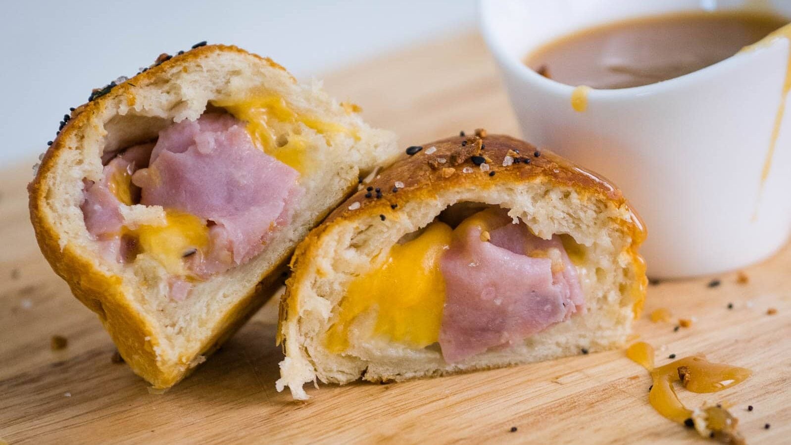 Ham and cheese biscuits cut in half with mustard dipping sauce.