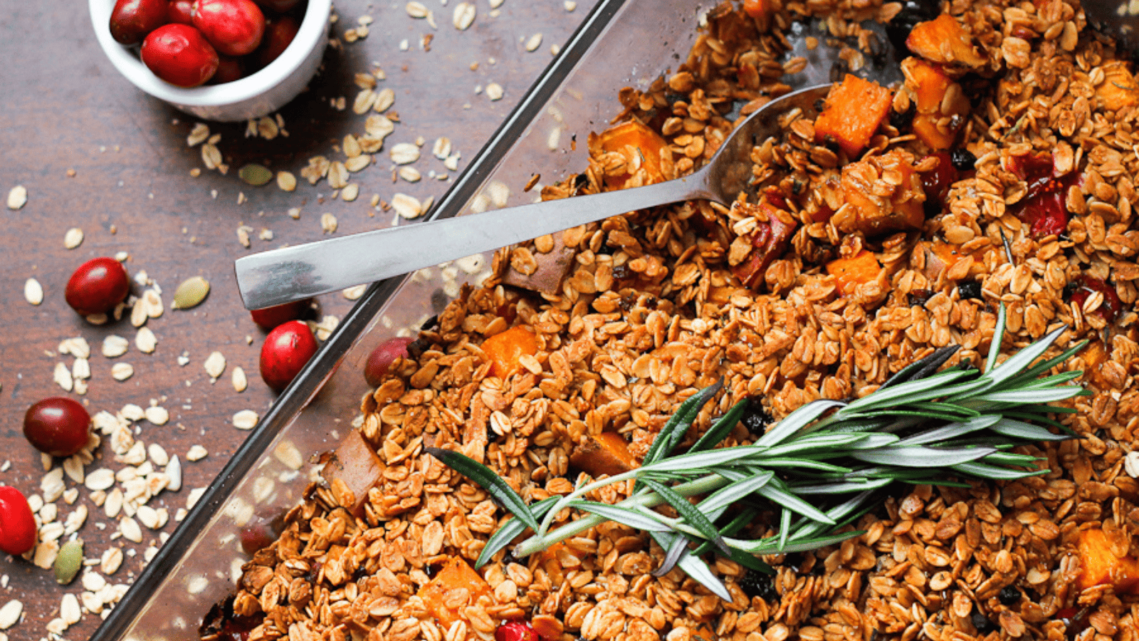 Baked almond, cranberry, and sweet potato stuffing with oats and rosemary in a glass dish.