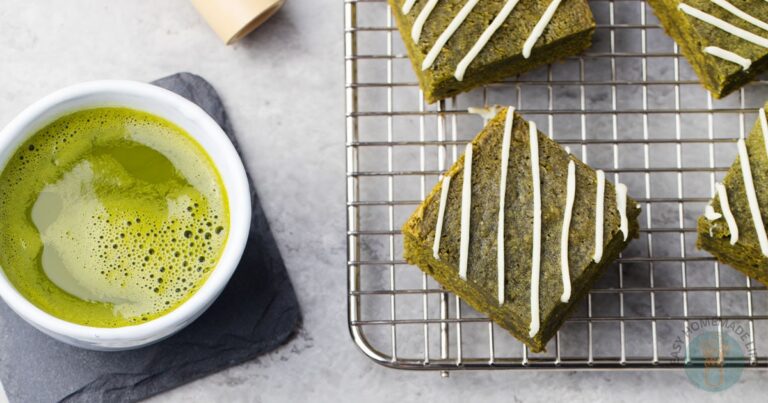A cup of green matcha tea sits beside three matcha brownies.