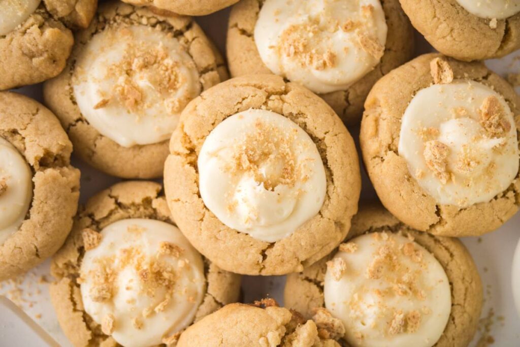 Close-up of several cookies topped with white frosting and sprinkled with crumbs, arranged closely together.