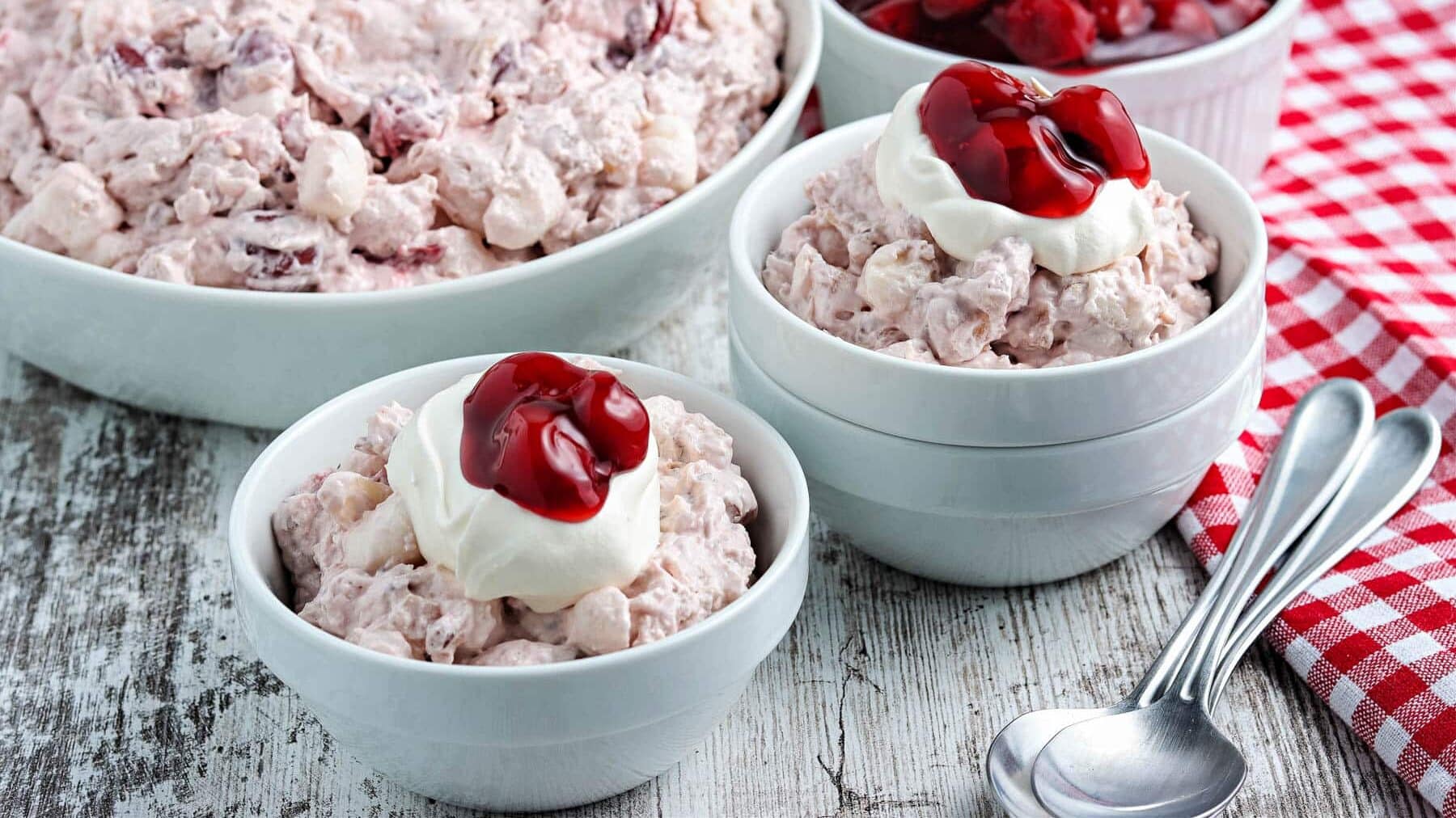 Cherry fluff salad in blue bowls with whipped cream.