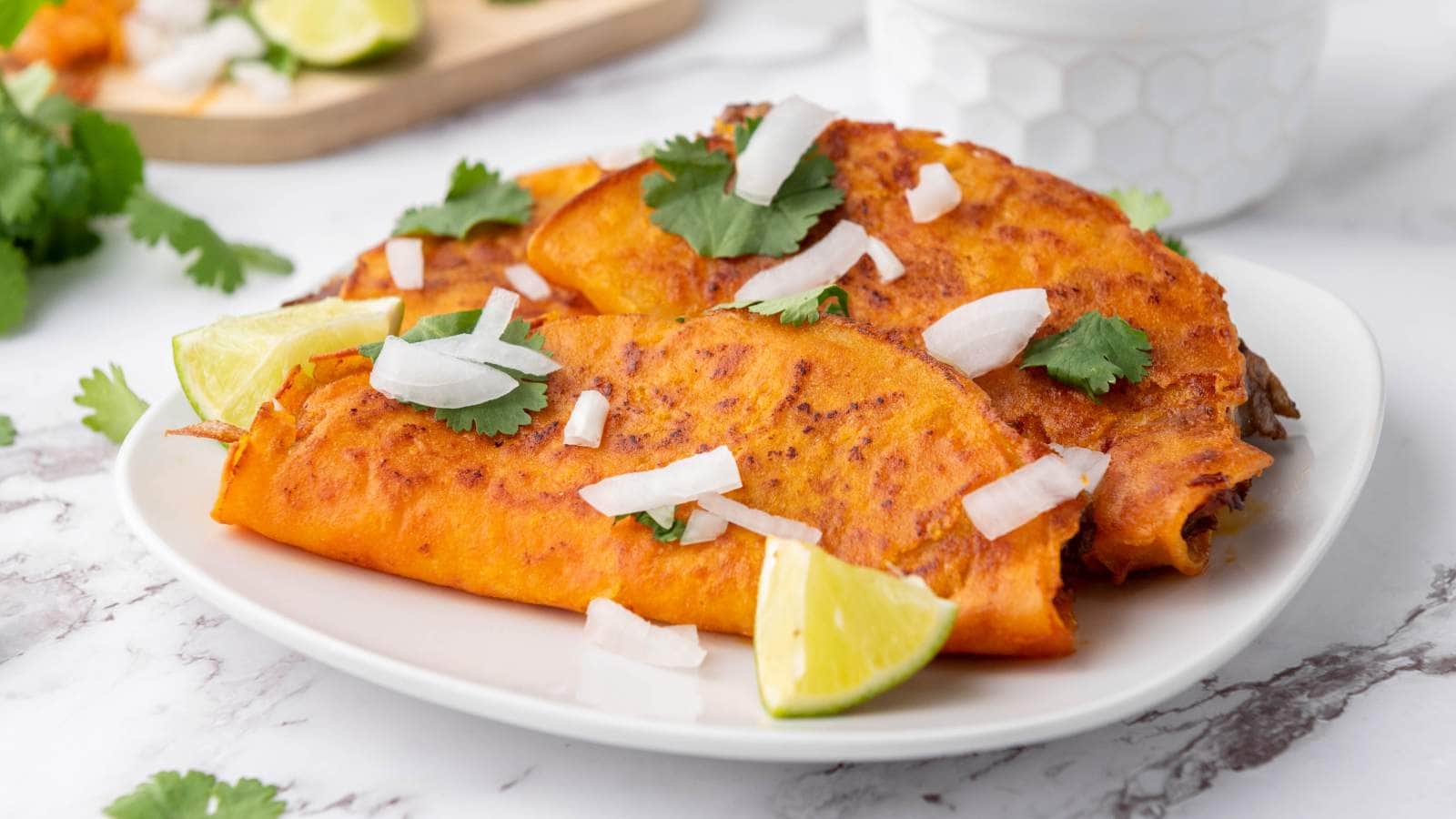 A quesabirria tacos topped with chopped onions, cilantro, and lime wedge.
