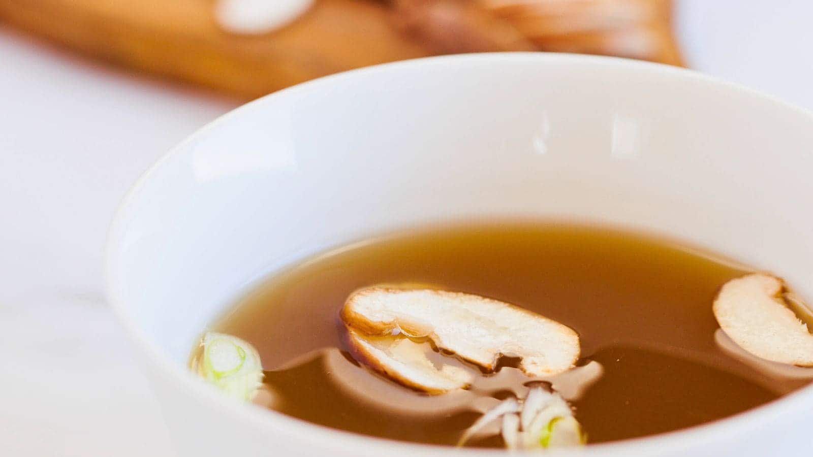 Close up on Shiitake Dashi Broth with mushroom slices floating.