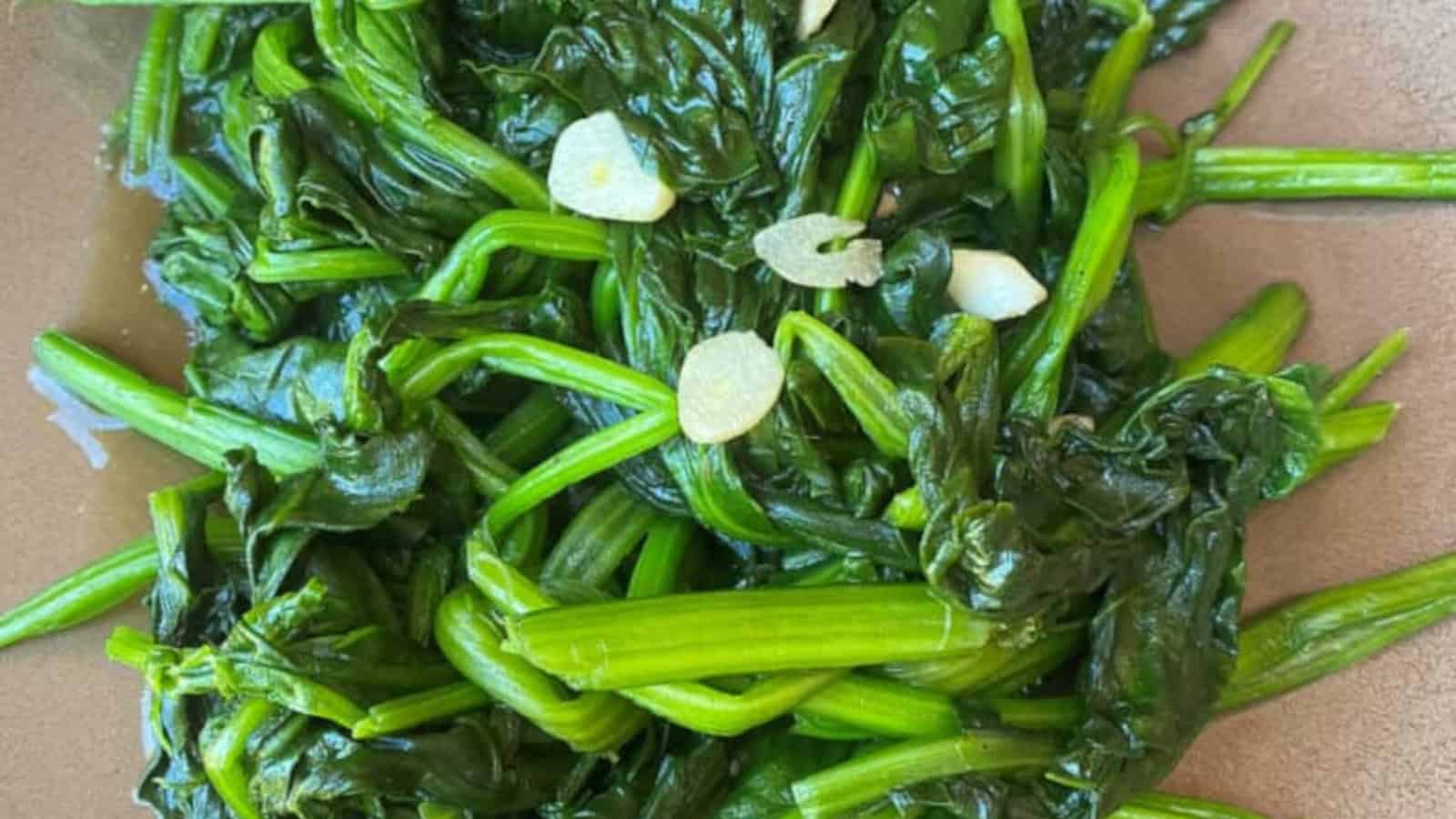 Healthy and flavorful stir-fried Taiwanese spinach with garlic on a brown plate.