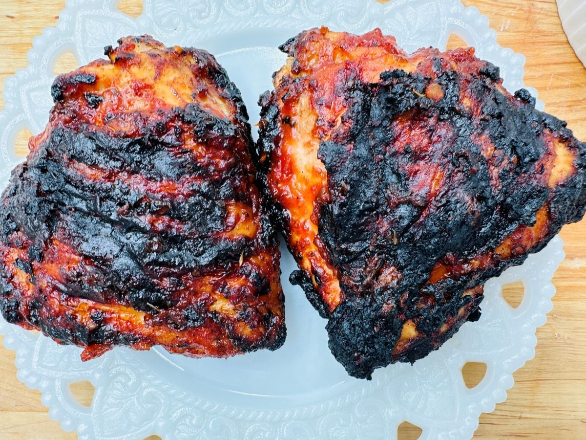 Two barbecue chicken thighs on white plate.