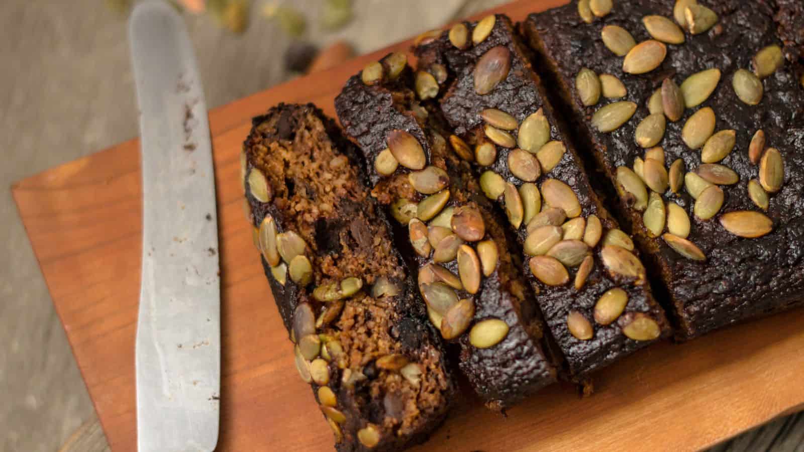 A slice of pumpkin bread on a wooden cutting board.