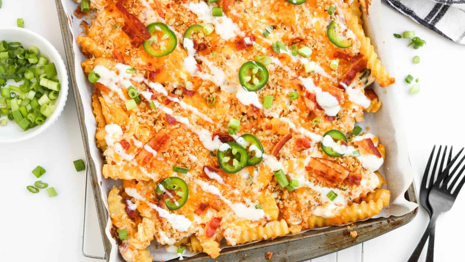 Crinkle-cut fries topped with cheese, bacon, jalapeños, green onions, and drizzled with ranch sauce.