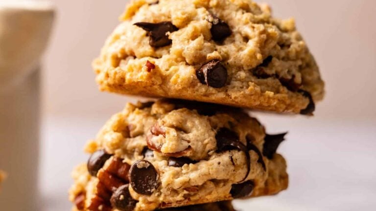 Two chocolate chip cookies with nuts stacked on top of each other in close-up view.